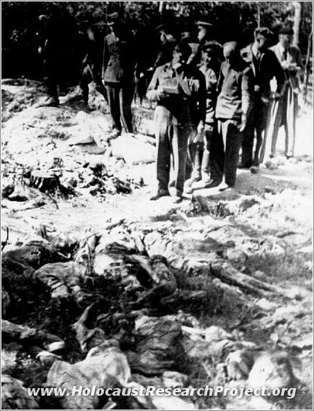 Military correspondents standing beside the remains of victims murdered in the Majdanek camp